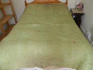 Green quilt with large dirty patch at edge