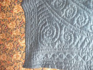 Blue paisley quilt with corner of plain blue reverse side