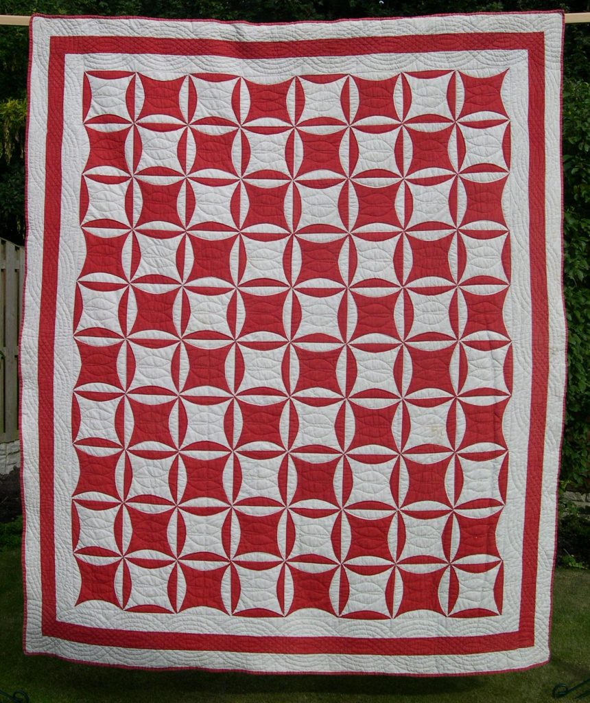 Red and white quilt with circular motifs