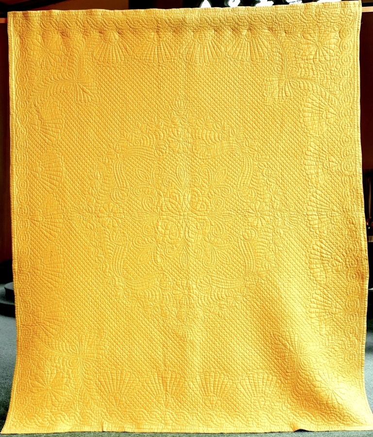 Large yellow hand-stitched quilt