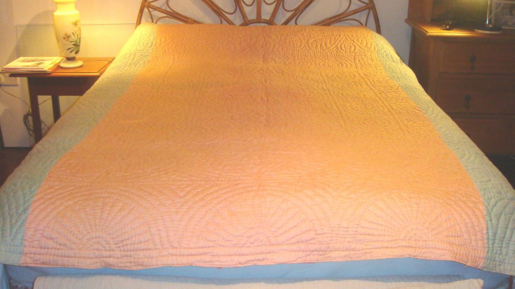 Salmon pink and blue quilt on bed