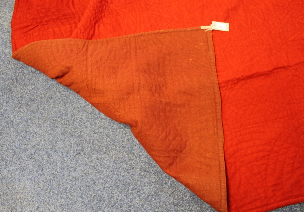 Bright red quilt with russet back showing on folded over corner.