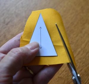 Yellow fabric being cut out using card triangle template