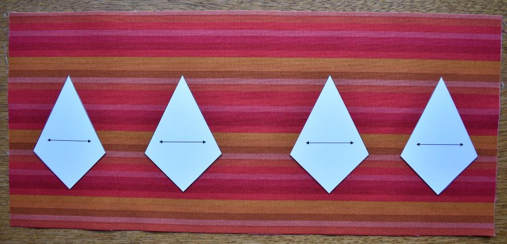 Four card templates lined up on striped fabric placed horizontally