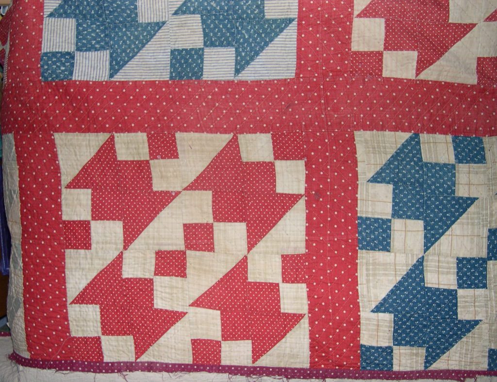 Four red and cream patchwork blocks arranged next to each other