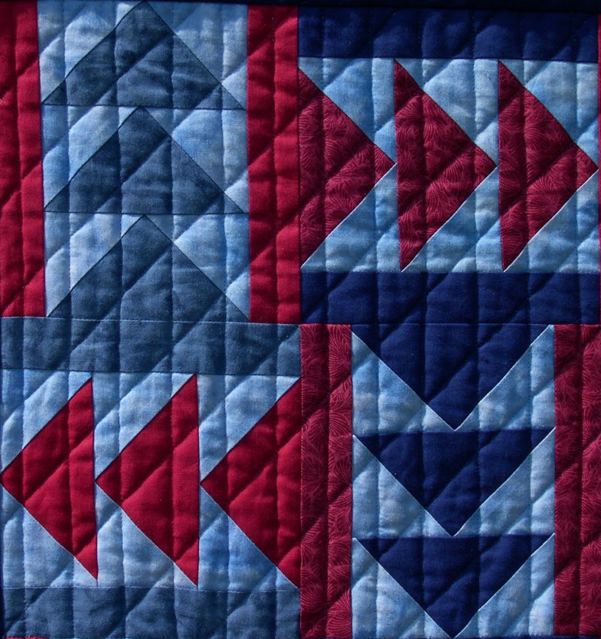 Vertical and diagonal lines of quilting over patchwork