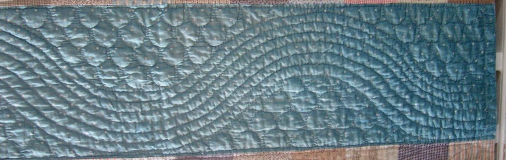 Large waving lines of stitching flow along the blue fabric strip