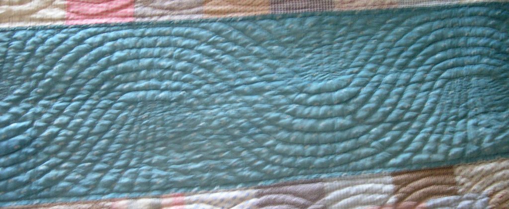 Large waving lines of stitching flow along the blue fabric strip, with a spray infill