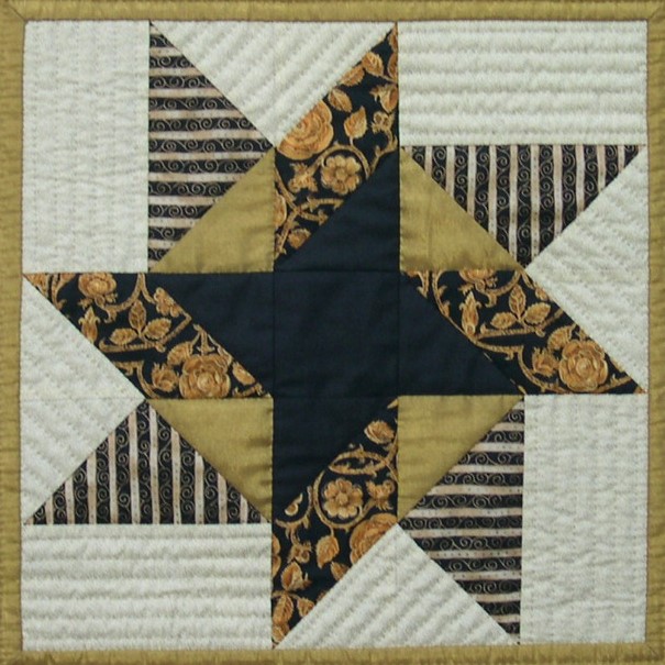 Black, gold and cream star block, with simple lines of quilting in cream background.