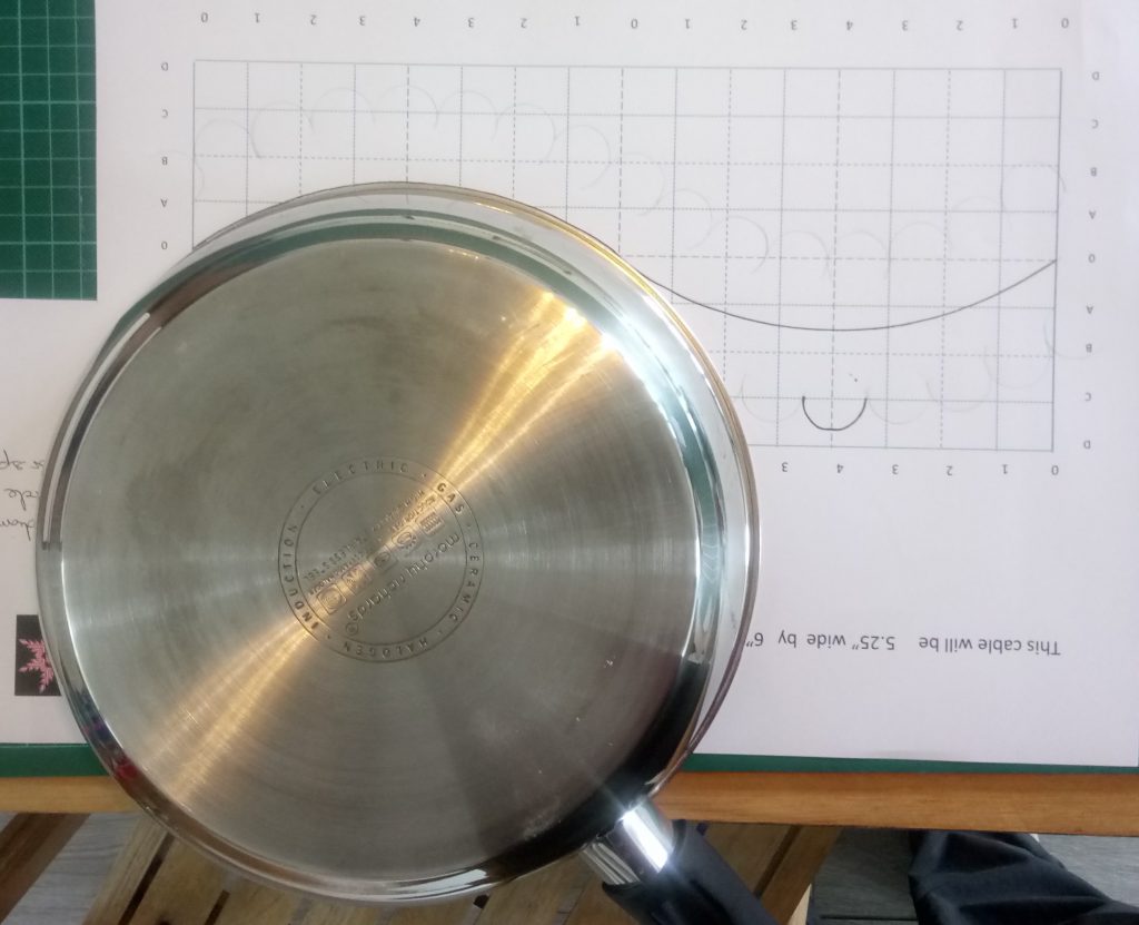 Frying pan laid upside-down, being used to draw curve