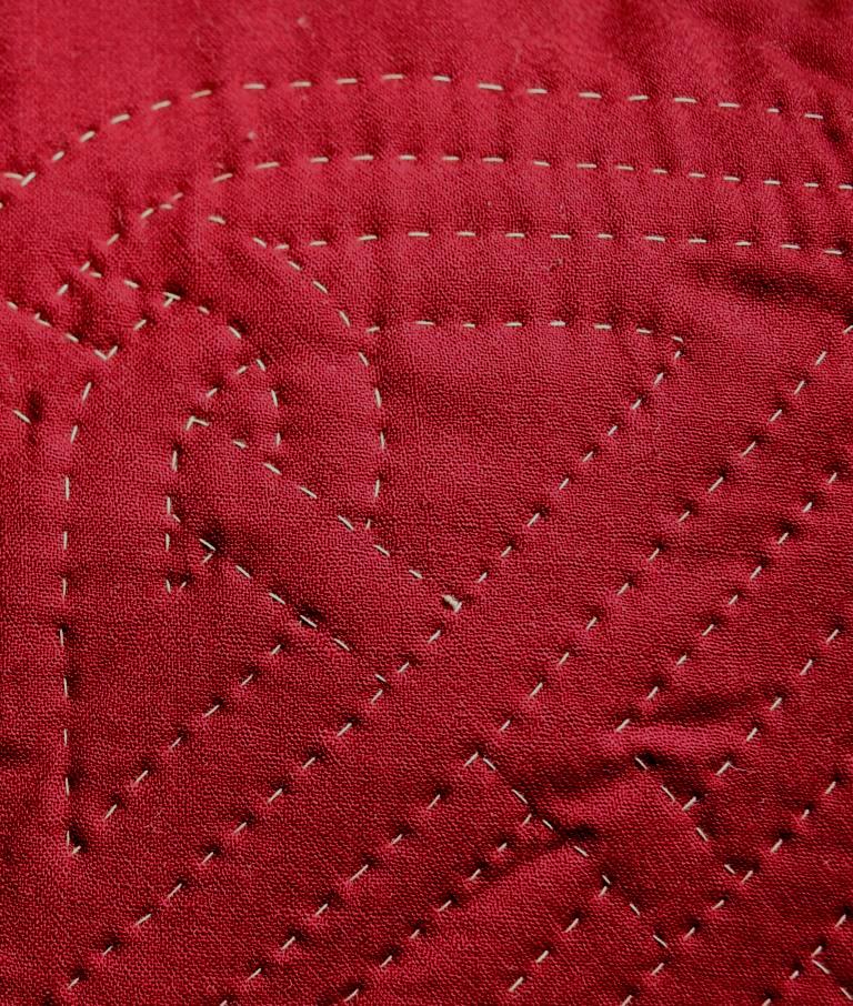 Celtic knot motif in white on burgundy wool fabric