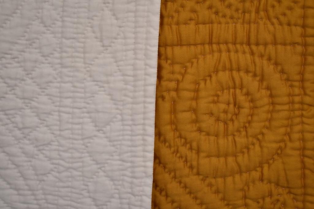 White quilting has small stitches and a flat effect; deep yellow quilt has larger stitches, but the design is more prominent