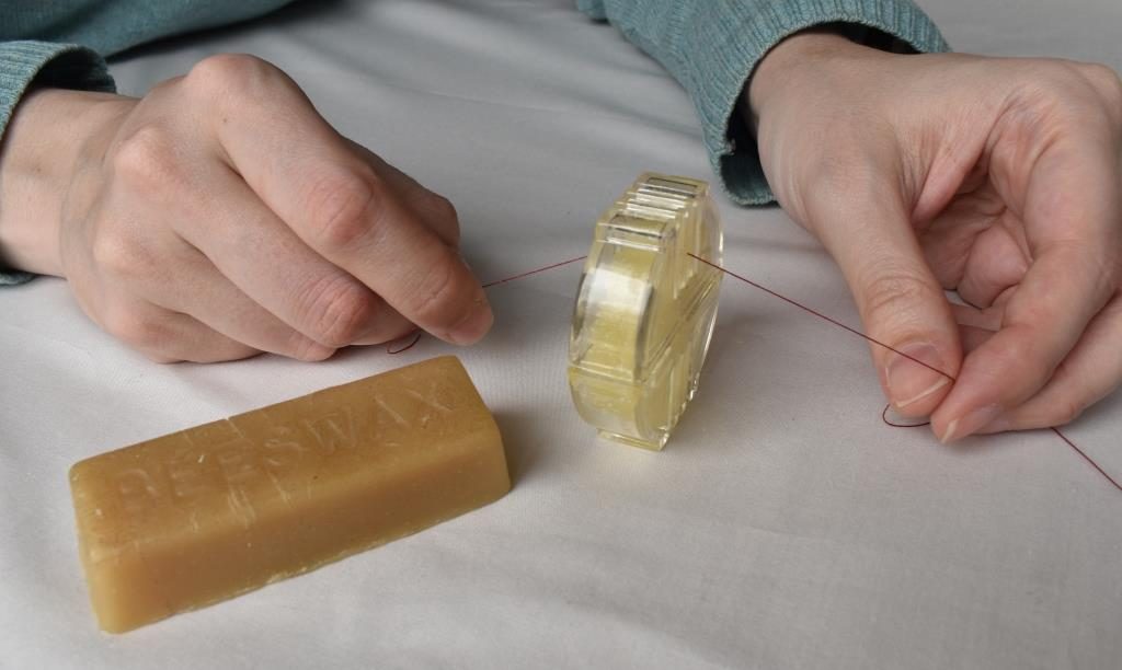 Thread being drawn through a cake of beeswax in a plastic holder