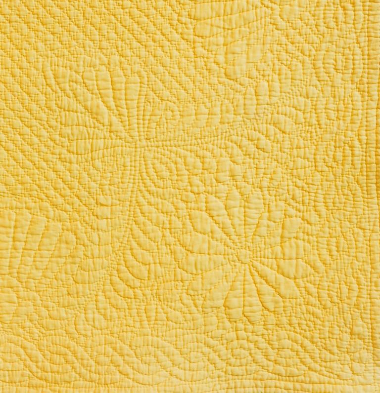 Flower and feather motifs quilted onto yellow cloth