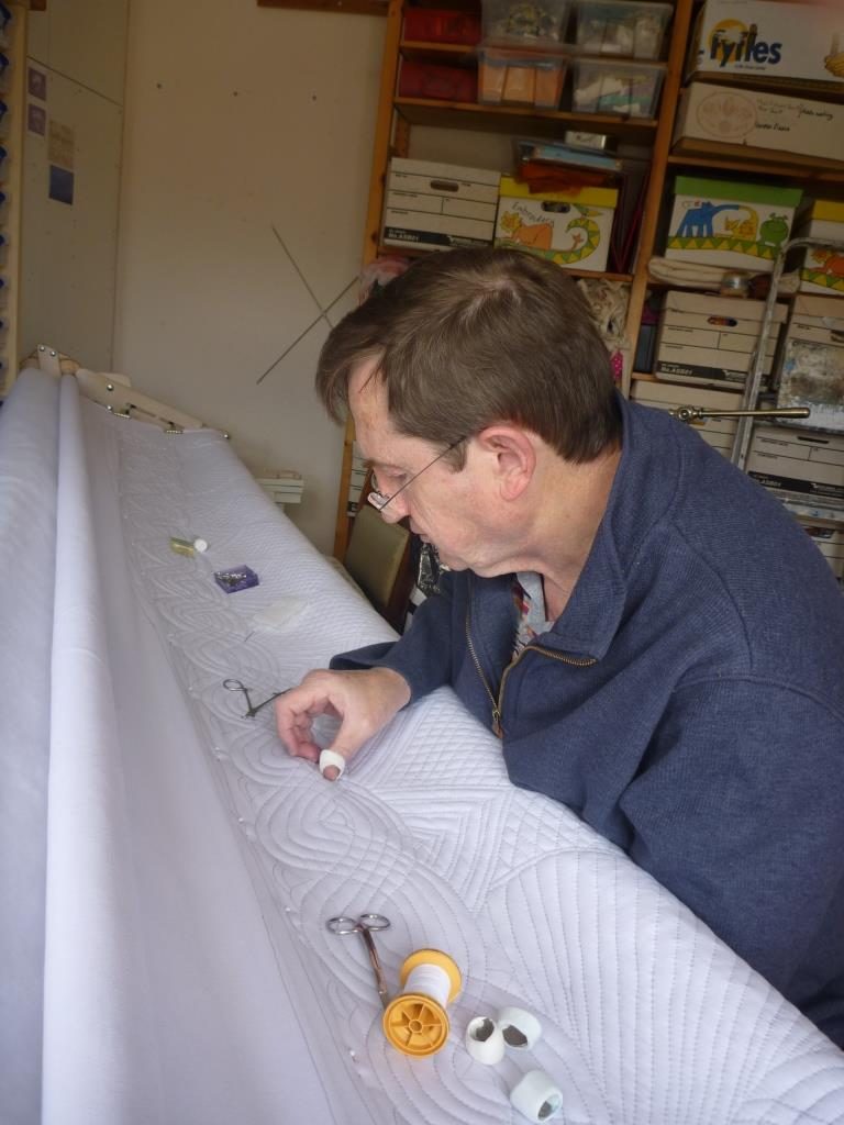 Man hand quilting on a very long frame
