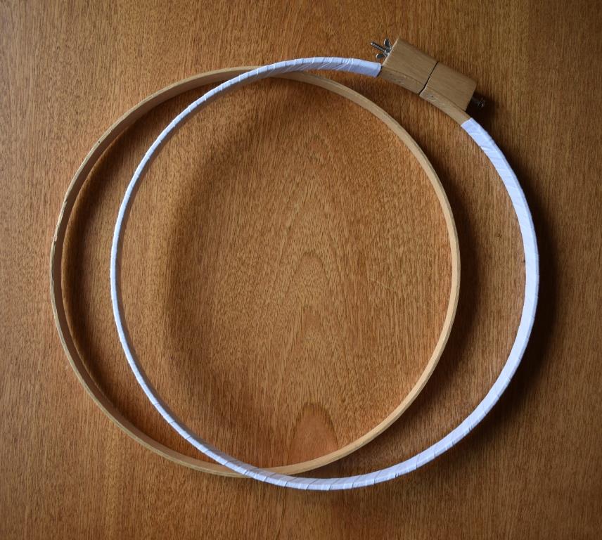 Two wooden rings. The outer one is bound with white tape, and has a wing not fastening.