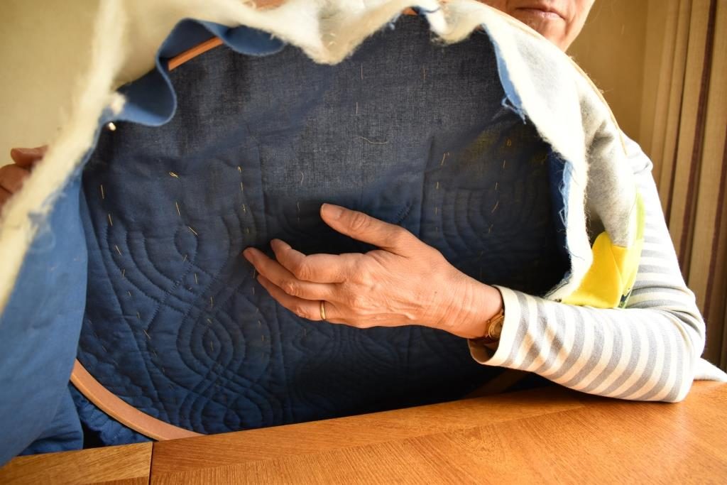 Arm under quilting hoop, with hand able to reach beyond centre area.