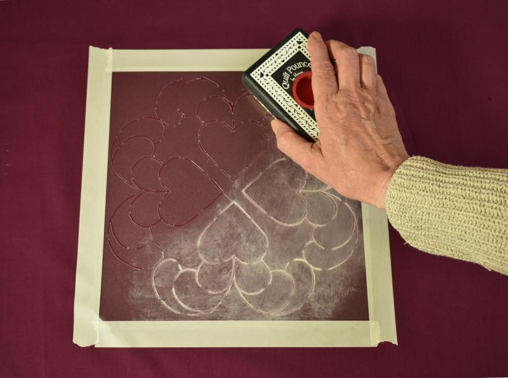 White chalk used in a "pounce pad" to mark a stenciled design on purple fabric.