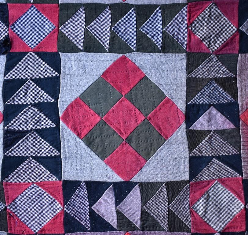 Red and green patchwork centre. Border of black and white check triangles on dark.