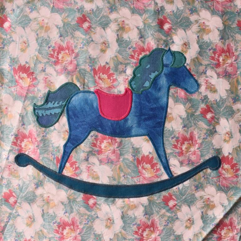 Blue rocking horse appliques onto floral background