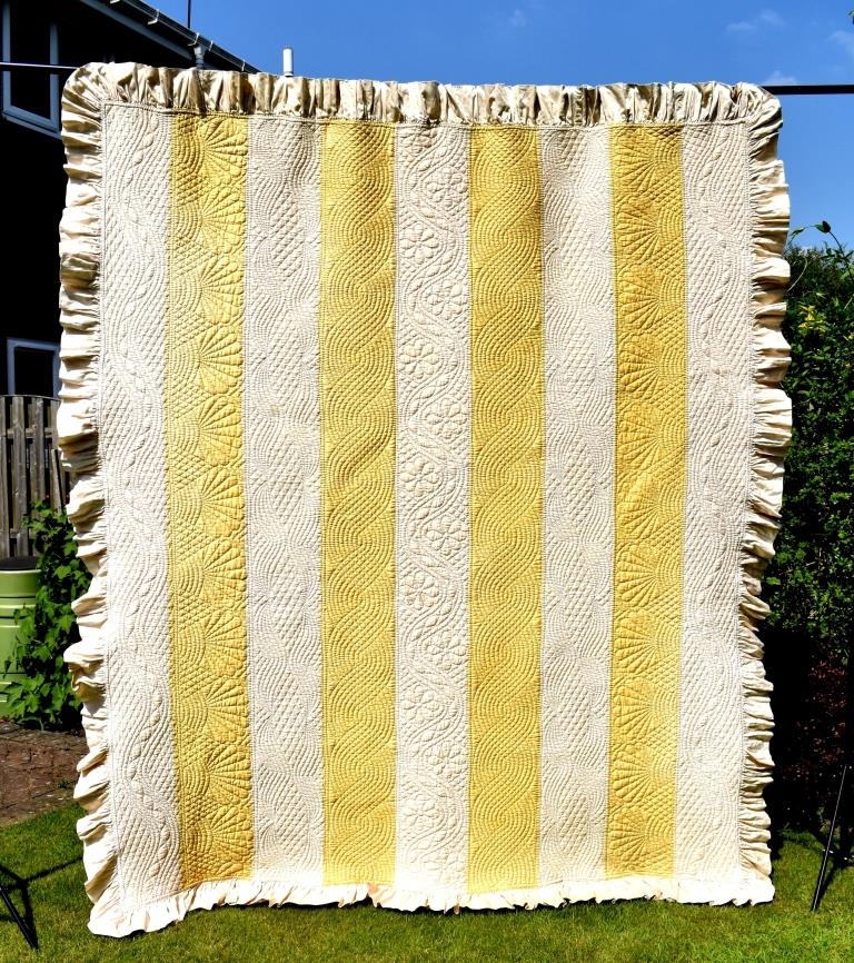 yellow and white striped quilt with quilting patterns running down strips